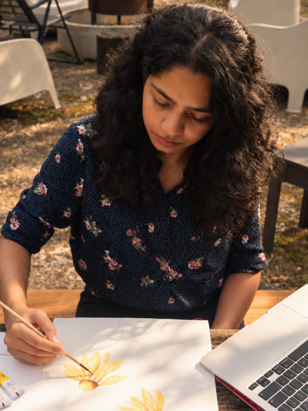 Painting yellow flowers in watercolour at an outdoor table