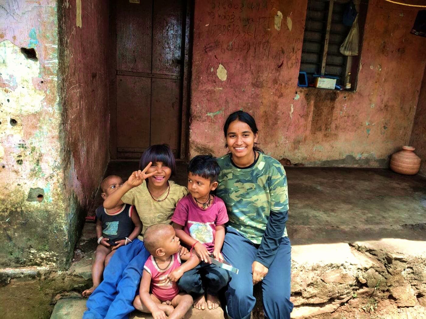 Nayana sitting with children on a doorstep at the estate