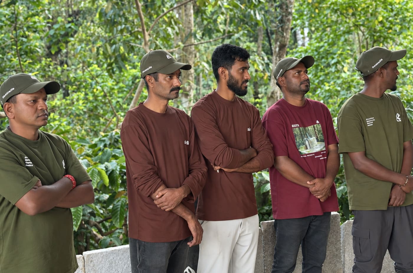 Five men of the Aura team in caps and Aura tops, arms folded