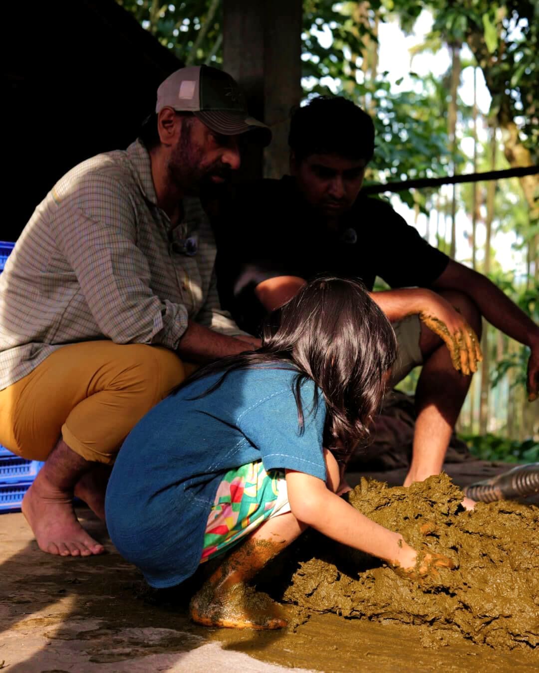 Adults and a child mixing the compost by hand