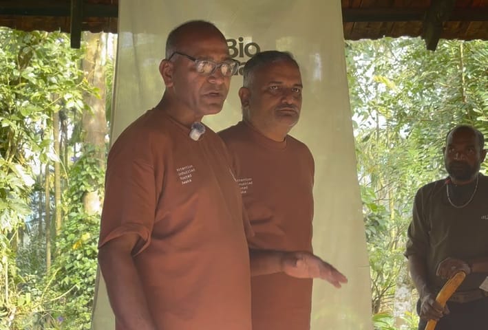 Rao sir and Arun sir, in Aura tops, explaining the cow pat pit under a shelter