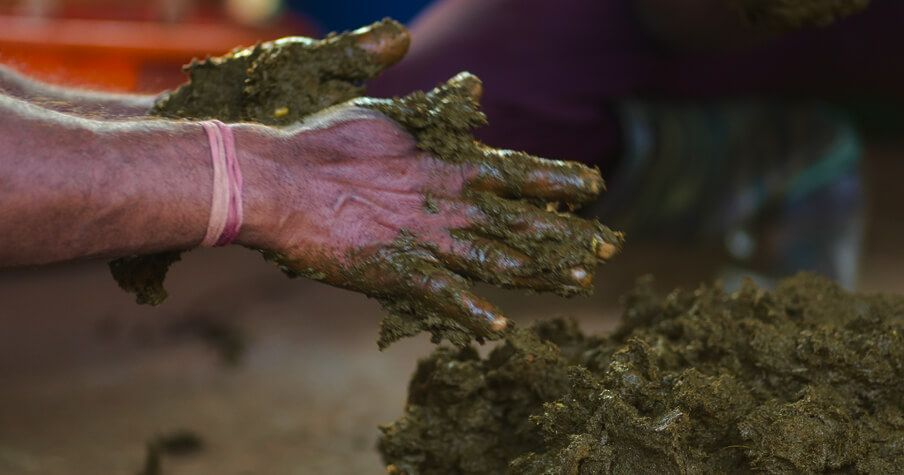 Hands deep in wet compost at the estate heap