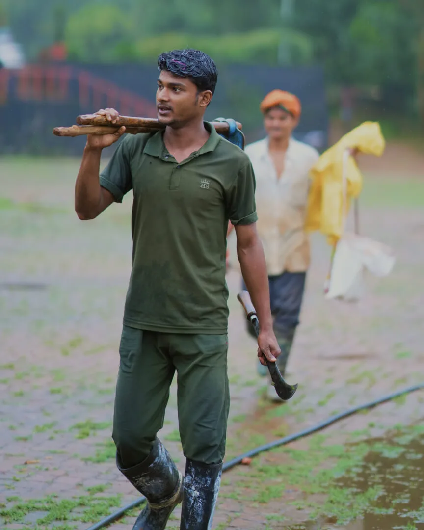 An estate worker crossing a block, tool in hand