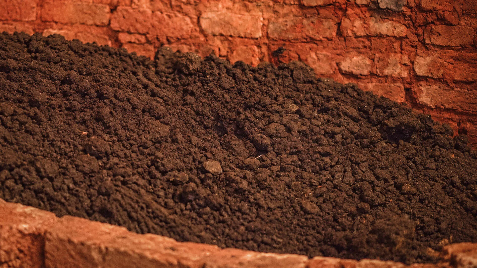 A cut bank of red laterite with dark topsoil above it